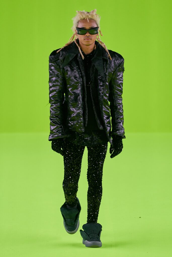 A fitted black leather jacket with long sleeves and zippered detail, paired with matching pants.