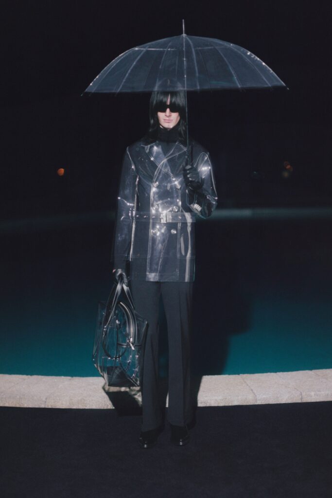 A fitted transparent jacket with long sleeves and collared design paired with black pants.