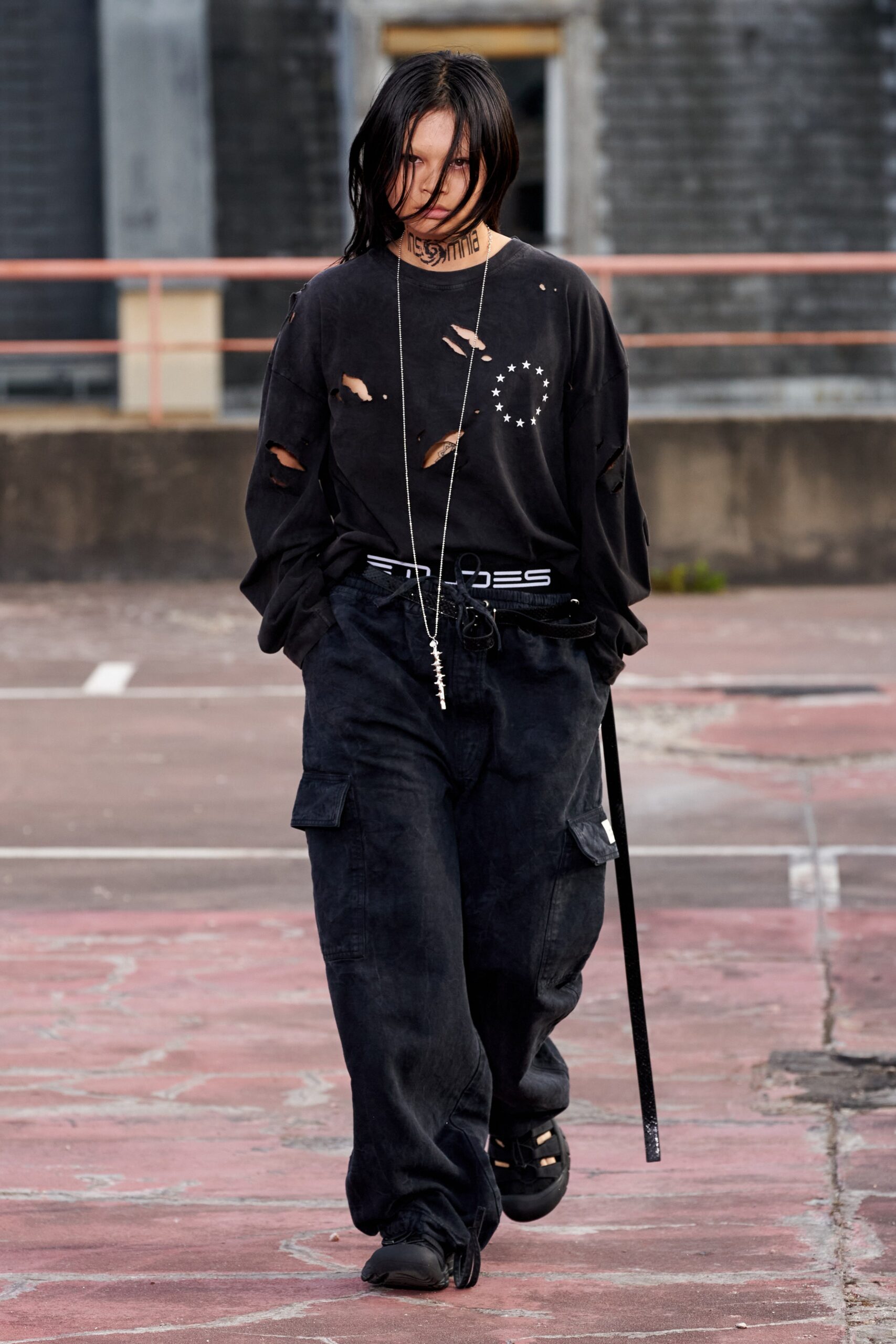 A relaxed black long-sleeve shirt with distressed details paired with black pants.