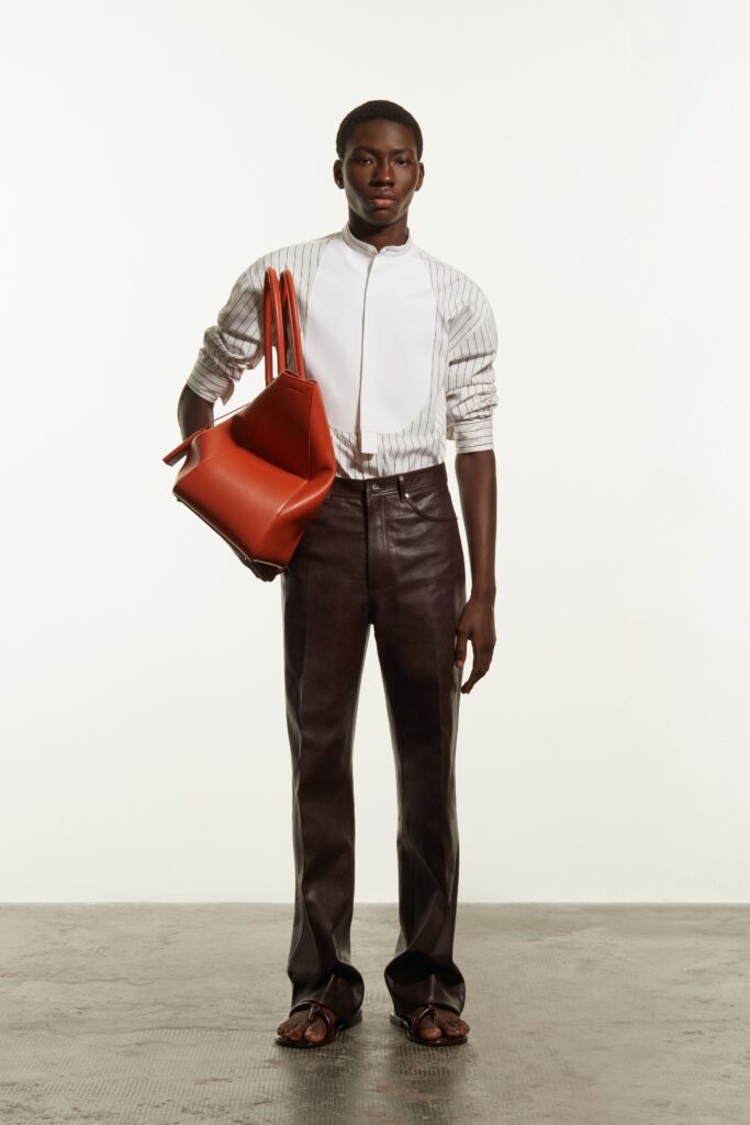 A fitted white striped shirt with a collar paired with sleek black leather pants.
