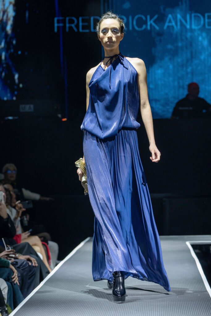 A relaxed blue silk sleeveless dress with a high neckline and draped design.