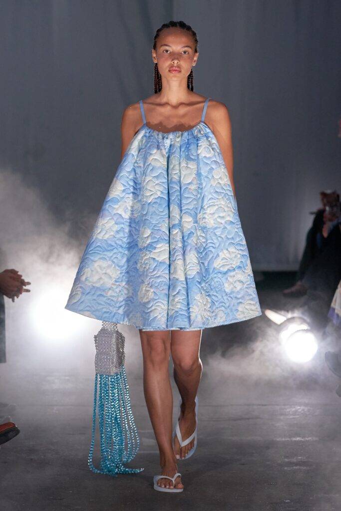 A relaxed blue cotton sleeveless dress with a high neckline and tiered design.