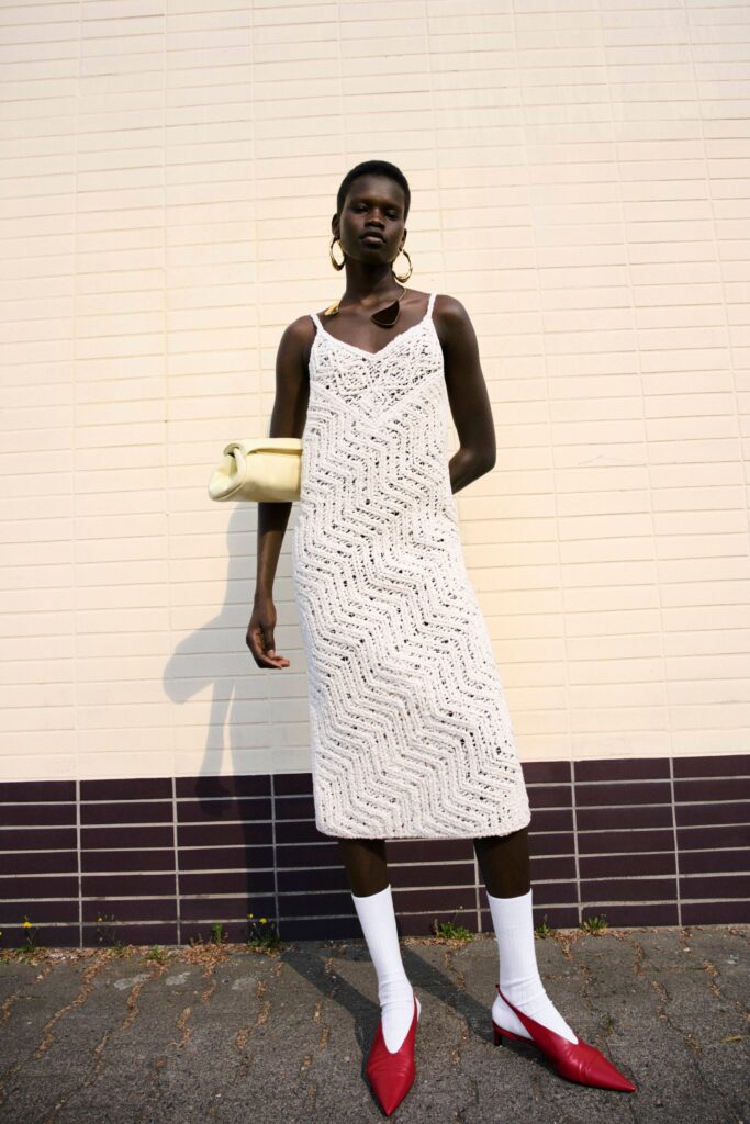 A fitted white cotton sleeveless dress with a V-neckline and tiered design.