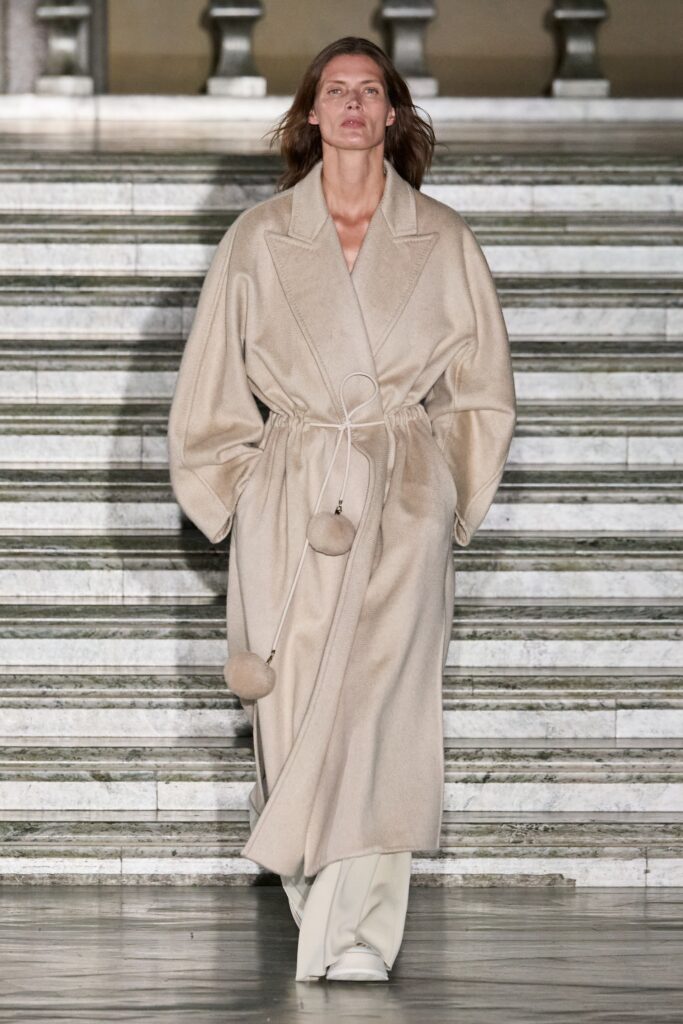 A relaxed beige wool coat with long sleeves and a belted design.