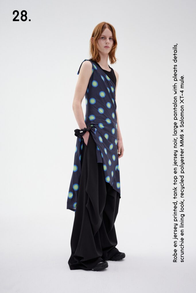 A relaxed blue printed sleeveless dress with an asymmetric design paired with black pants.