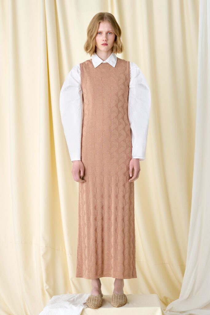 A fitted beige dress with a collared neckline and long sleeves.