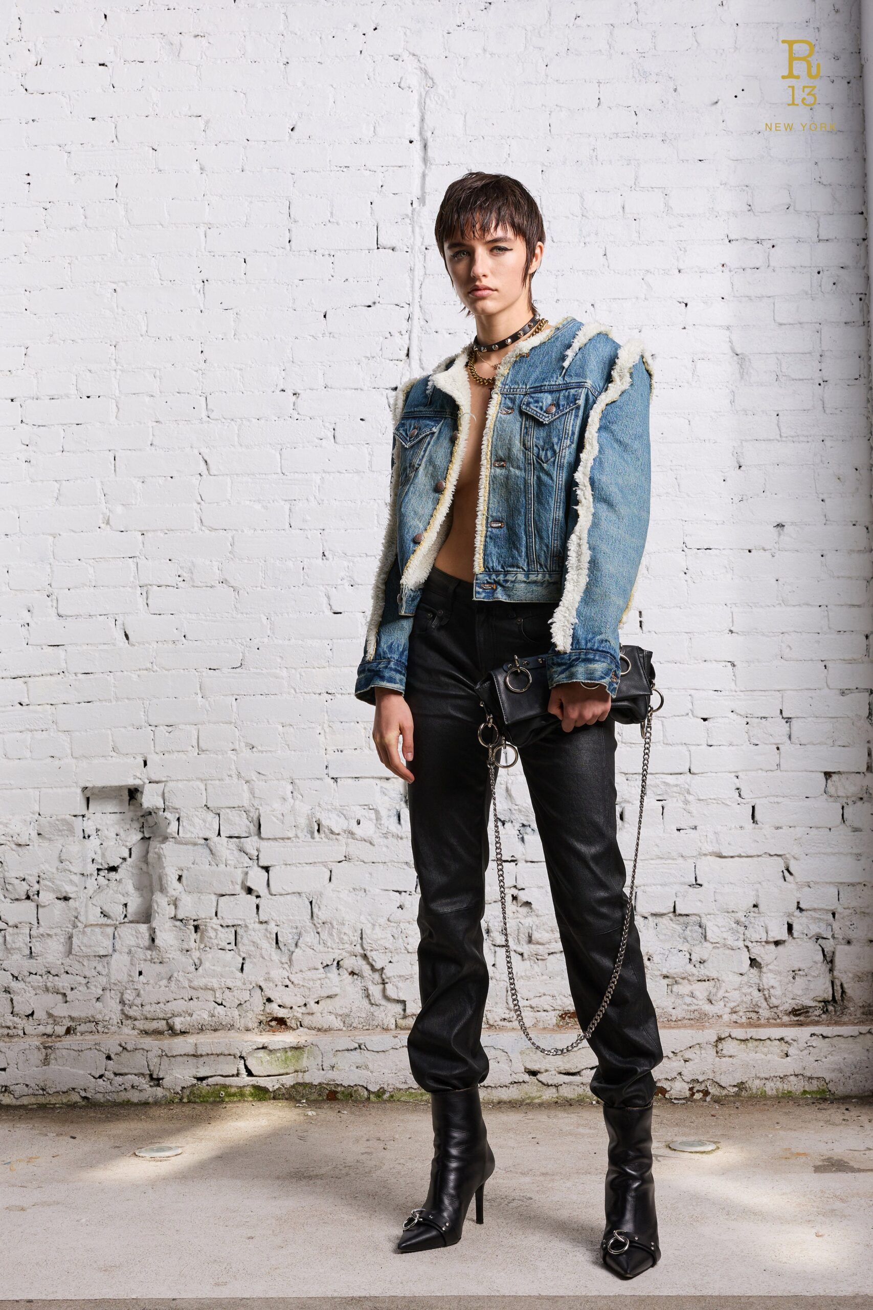 A fitted blue denim jacket with fringed detail paired with fitted black leather pants.