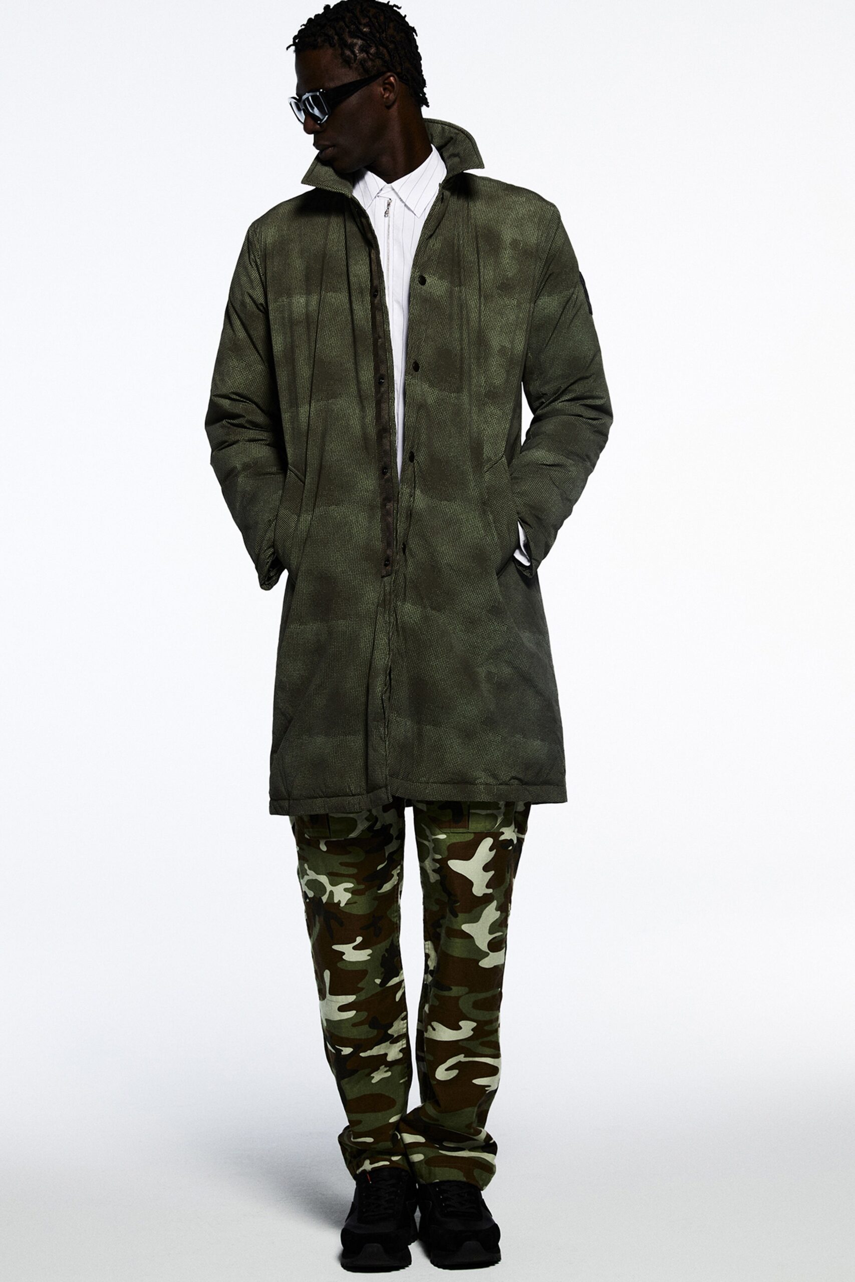 A relaxed green coat paired with camouflage pants featuring a collared design and buttoned front.
