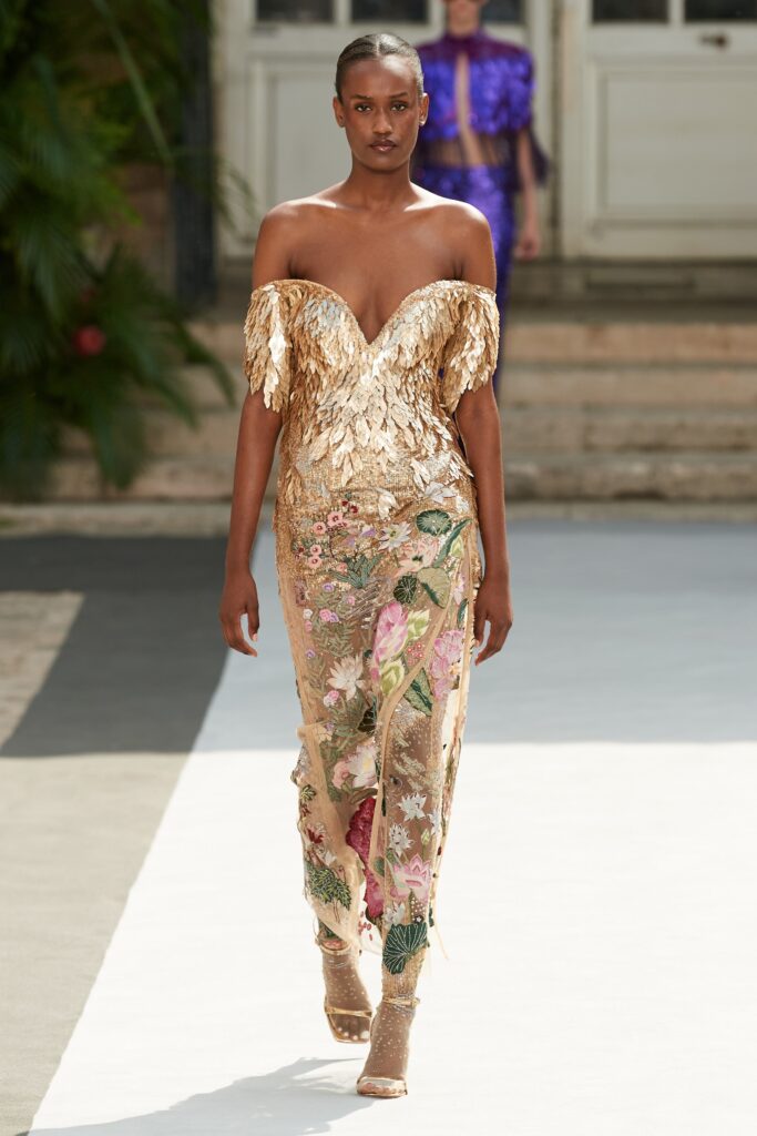 A fitted gold silk sleeveless dress with a V-neckline and intricate embroidery.