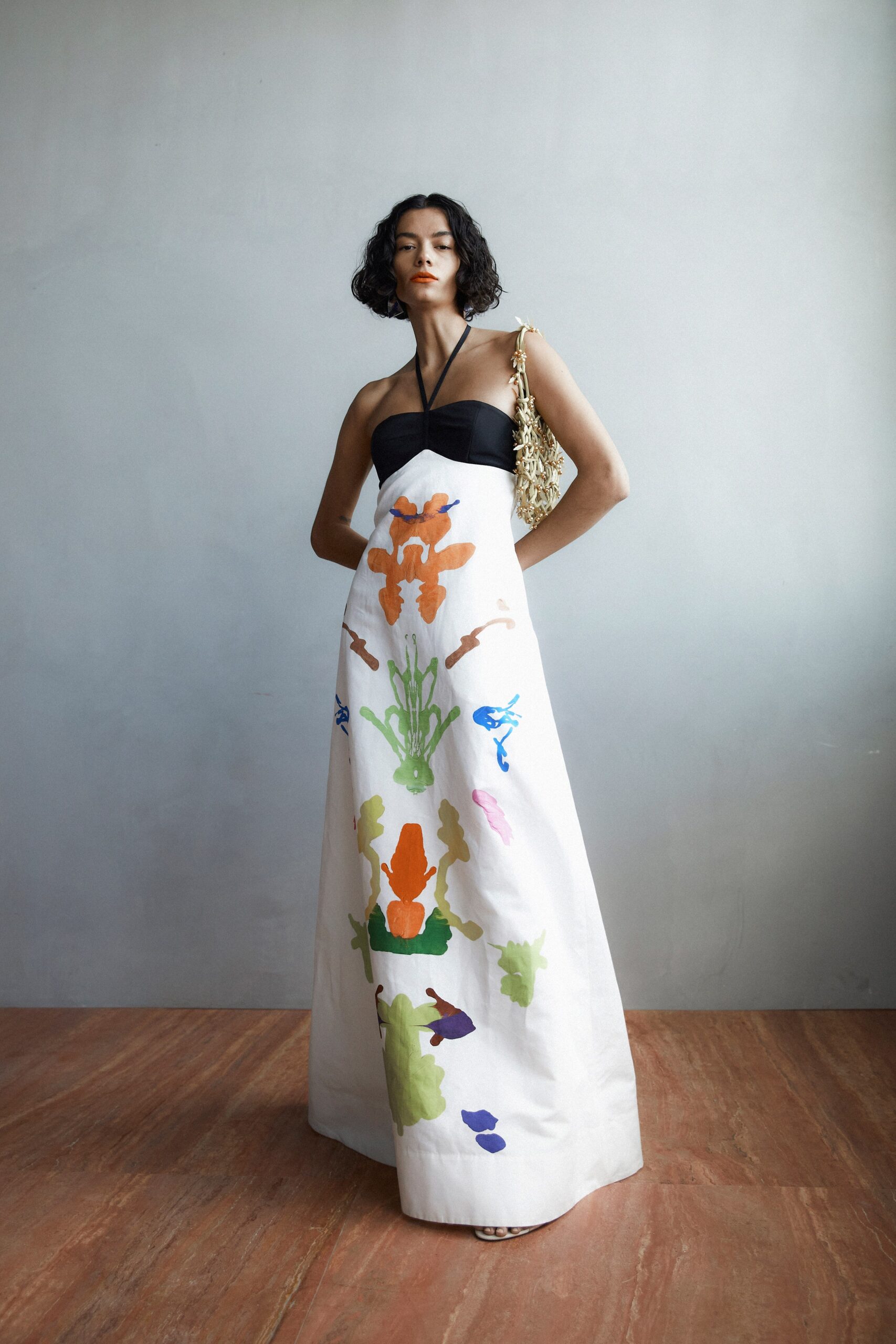 A fitted white dress with a halter neckline and vibrant printed details.