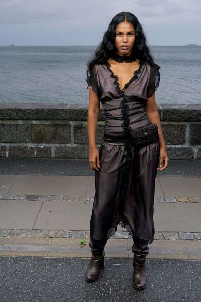 A fitted black silk dress with short sleeves, a V-neckline, and ruffled layered details.