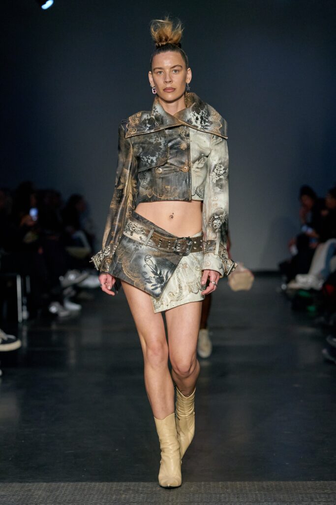 A fitted multicolor denim jacket with long sleeves and an asymmetric fringed skirt.