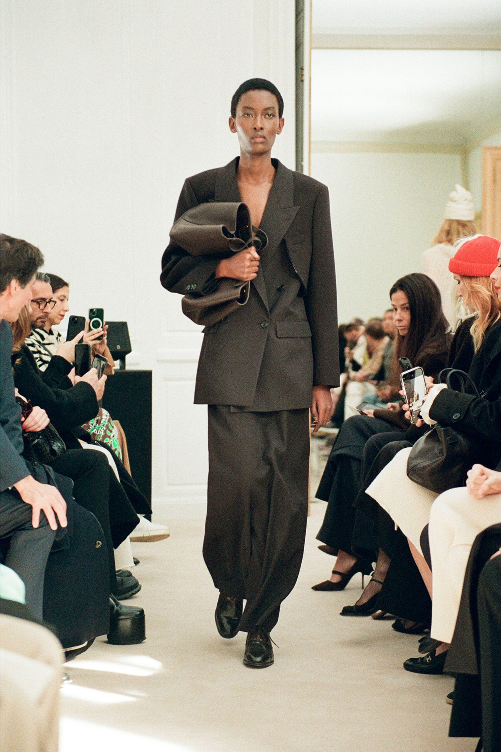 A tailored black wool suit with long sleeves and a collared design featuring straight-leg trousers.