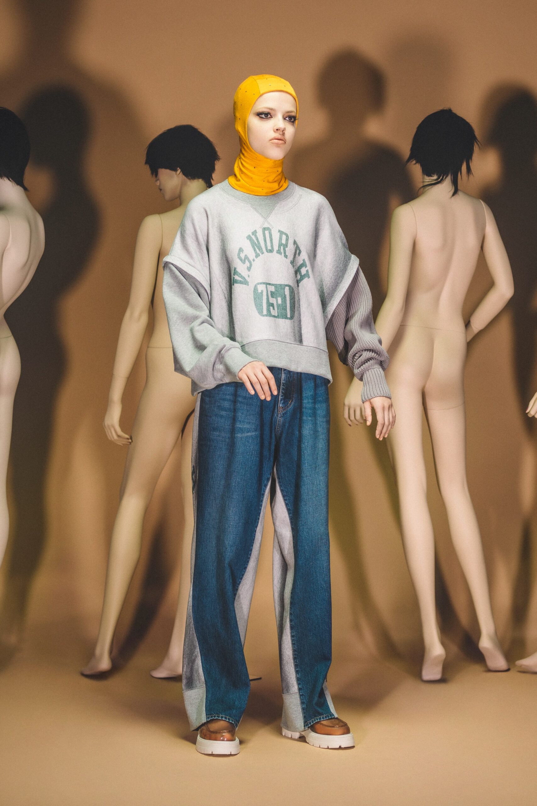 A relaxed gray long-sleeve sweater paired with blue denim pants featuring a layered design.
