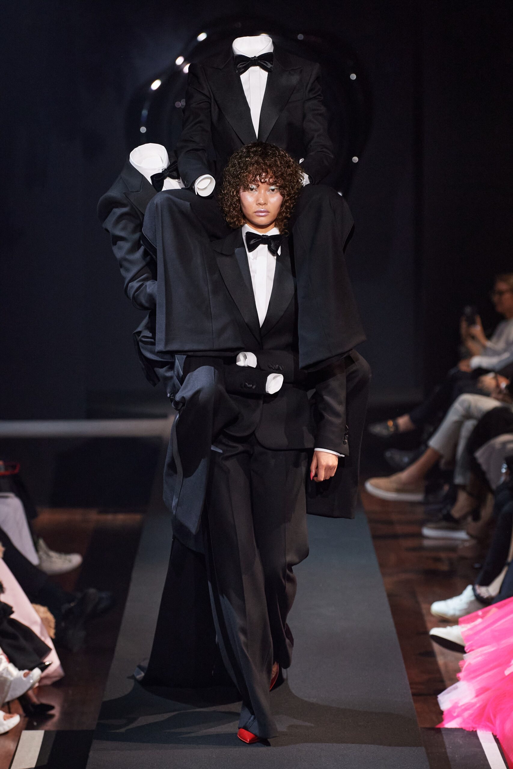 A structured black wool suit with long sleeves and an asymmetric design detail.