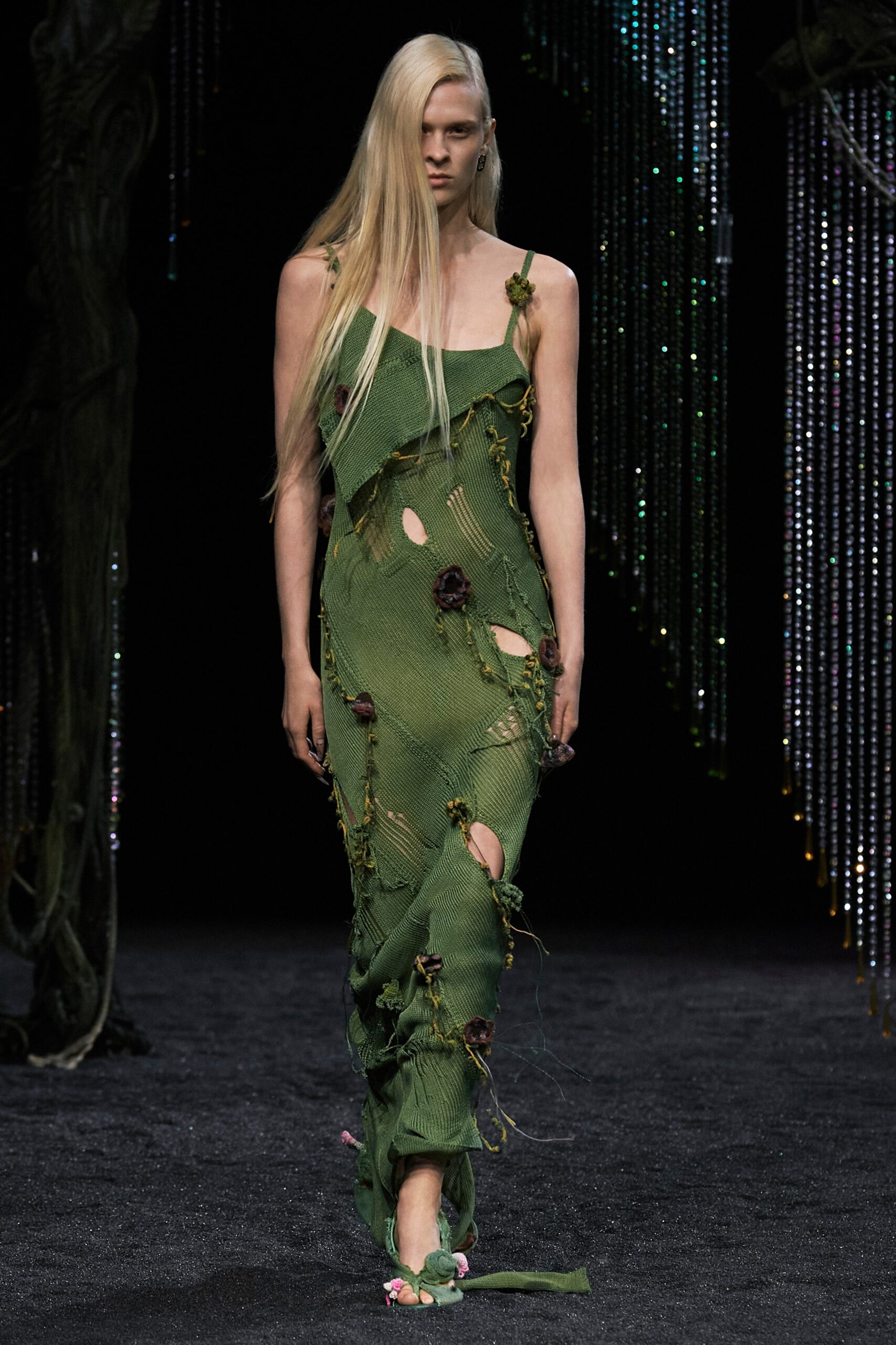 A fitted green sleeveless dress with an asymmetric design and draped details.