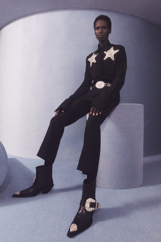 A black tailored blazer with long sleeves paired with matching black pants, featuring star embellishments.