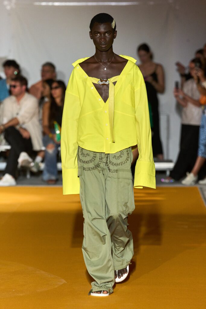 A relaxed yellow cotton shirt with a collared neckline paired with wide-leg green pants.