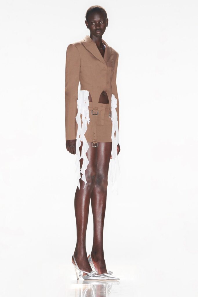 A fitted brown blazer paired with a layered asymmetric skirt featuring white details.