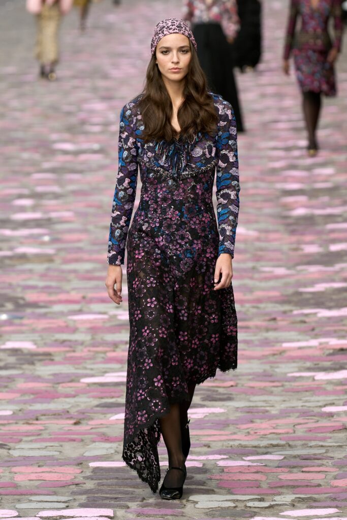A fitted black floral long-sleeve dress with a V-neckline and flared silhouette.