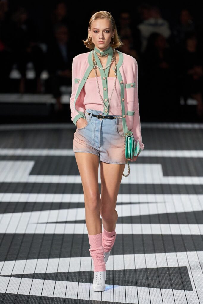 A fitted pink cotton long-sleeve top paired with color-blocked denim shorts.