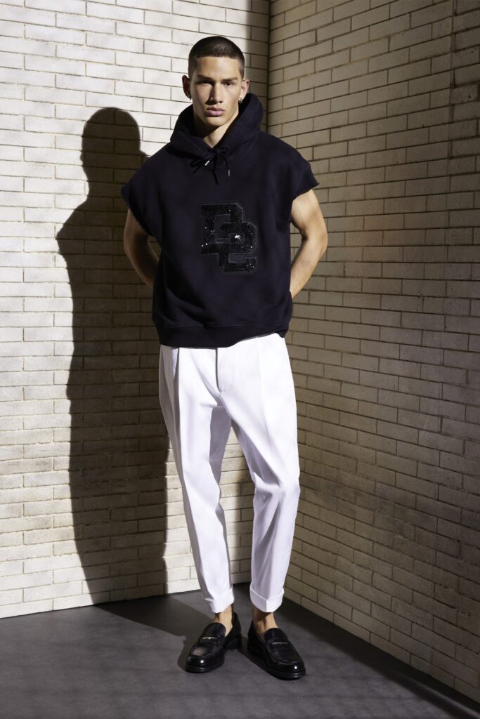 A relaxed black hoodie with a printed design paired with high-waisted white trousers.