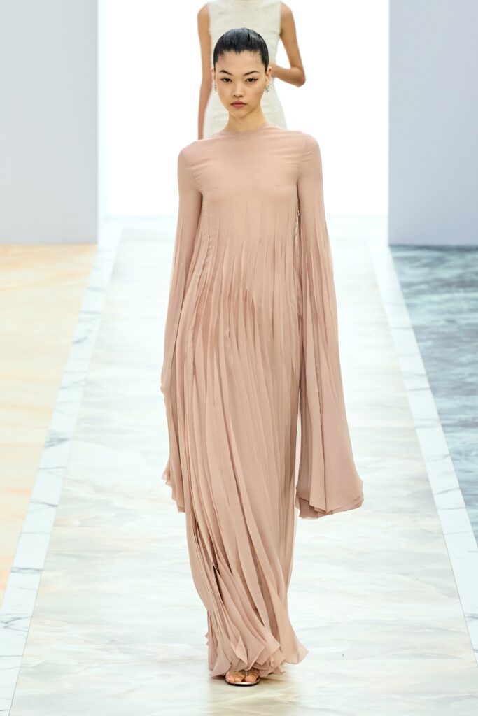 A relaxed beige silk dress with long sleeves and a pleated design.