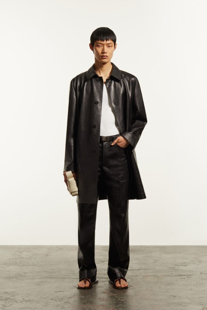 A fitted black leather coat with a collared neckline and straight-leg pants.