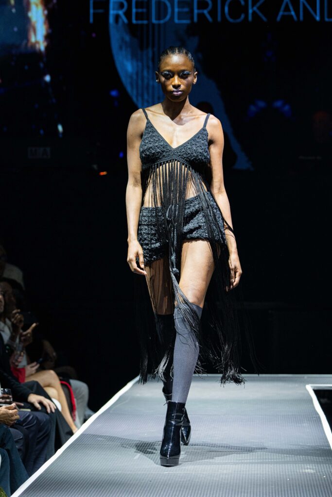 A fitted black lace sleeveless dress with a V-neckline and layered fringed detail.