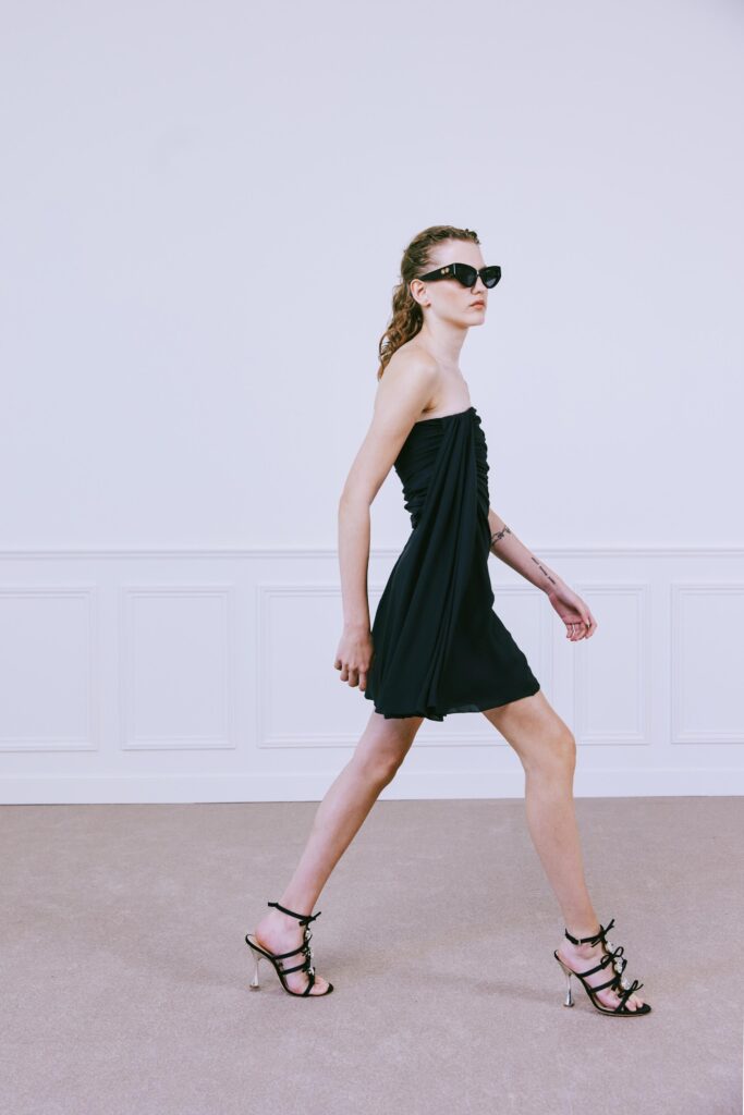 A fitted black sleeveless dress with a V-neckline and ruched detailing.