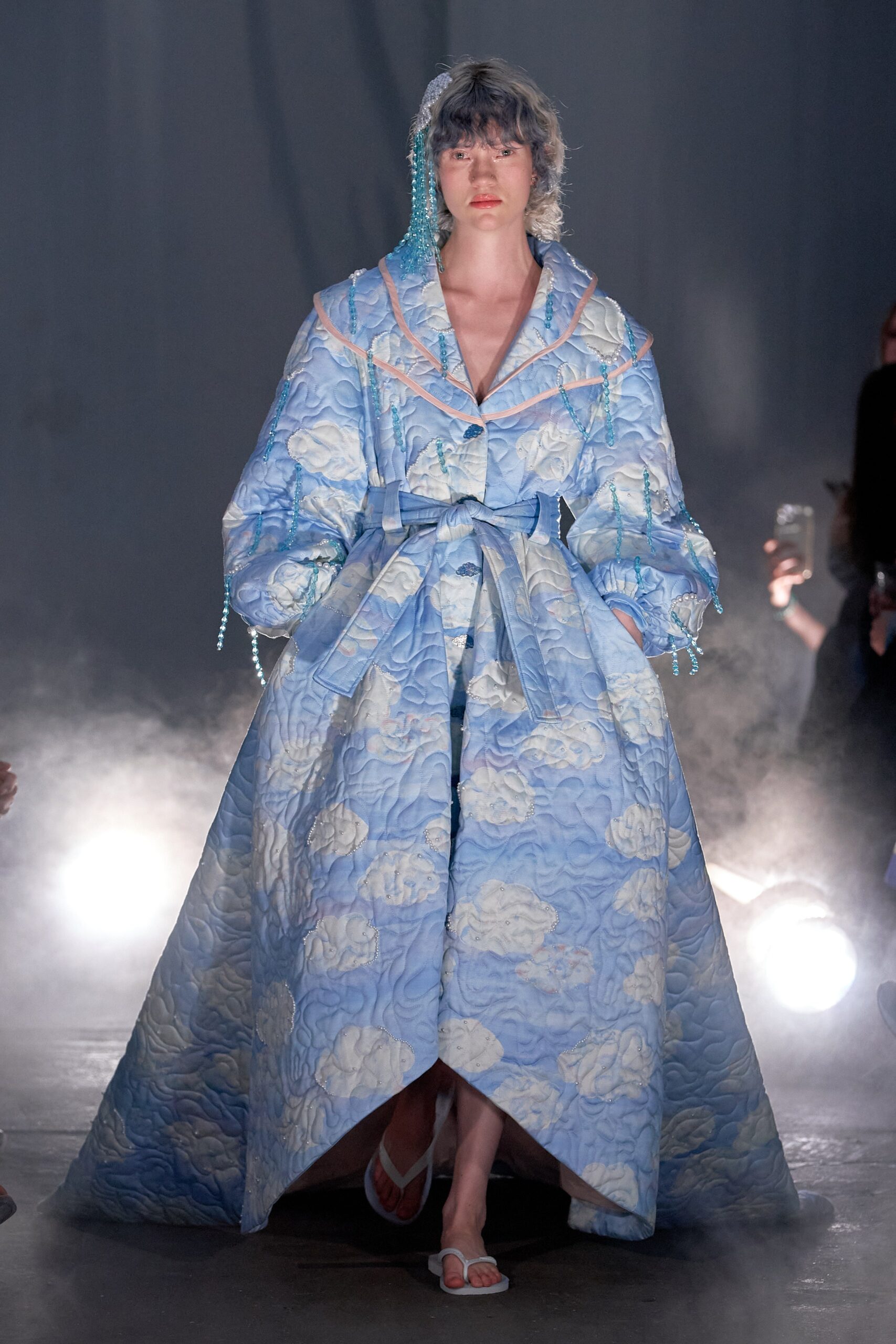 A relaxed blue cotton coat with long sleeves and a collared design, featuring a layered look.