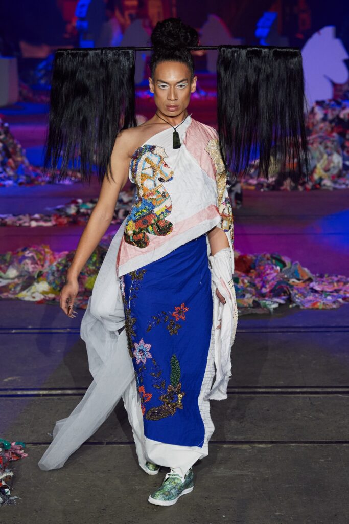 A fitted blue dress with white accents, featuring embroidery and an asymmetric design.