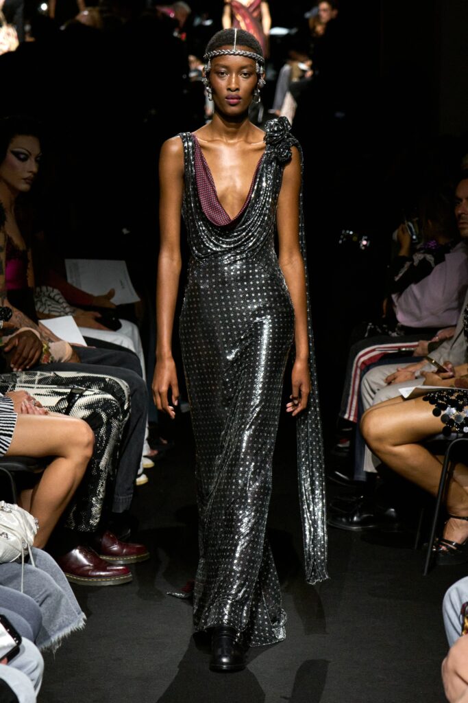 A fitted black silk dress with a sleeveless design and draped detail.