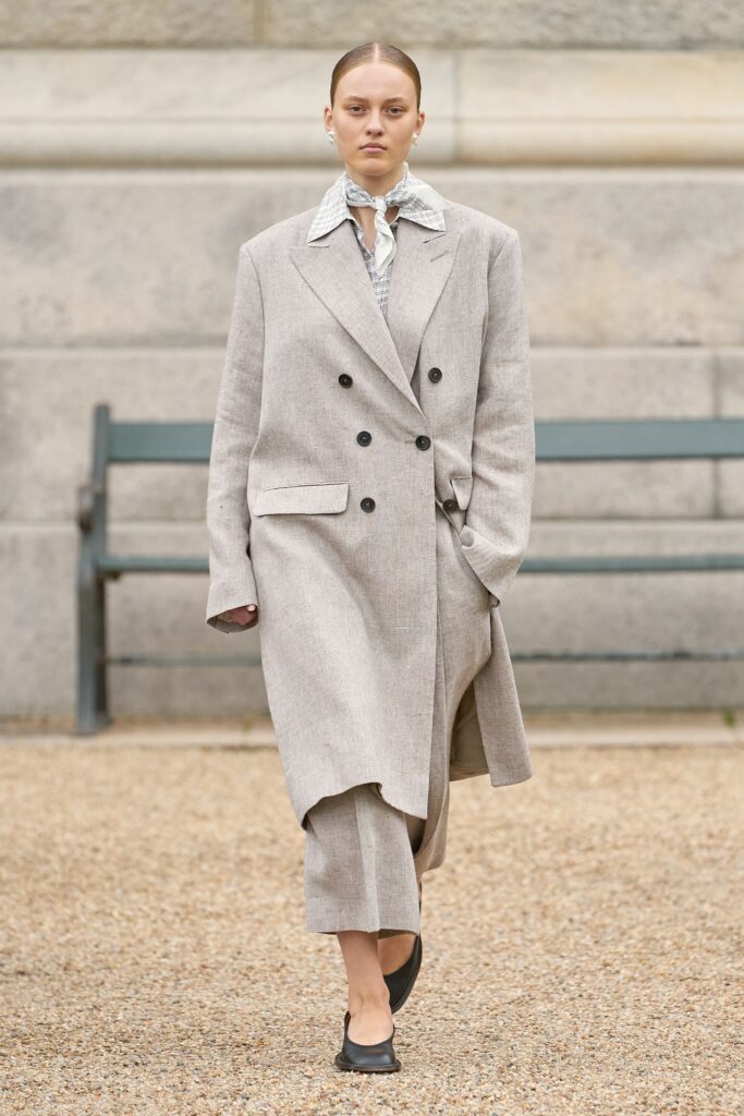 A relaxed beige wool coat with long sleeves, a collared neckline, and double-breasted design.