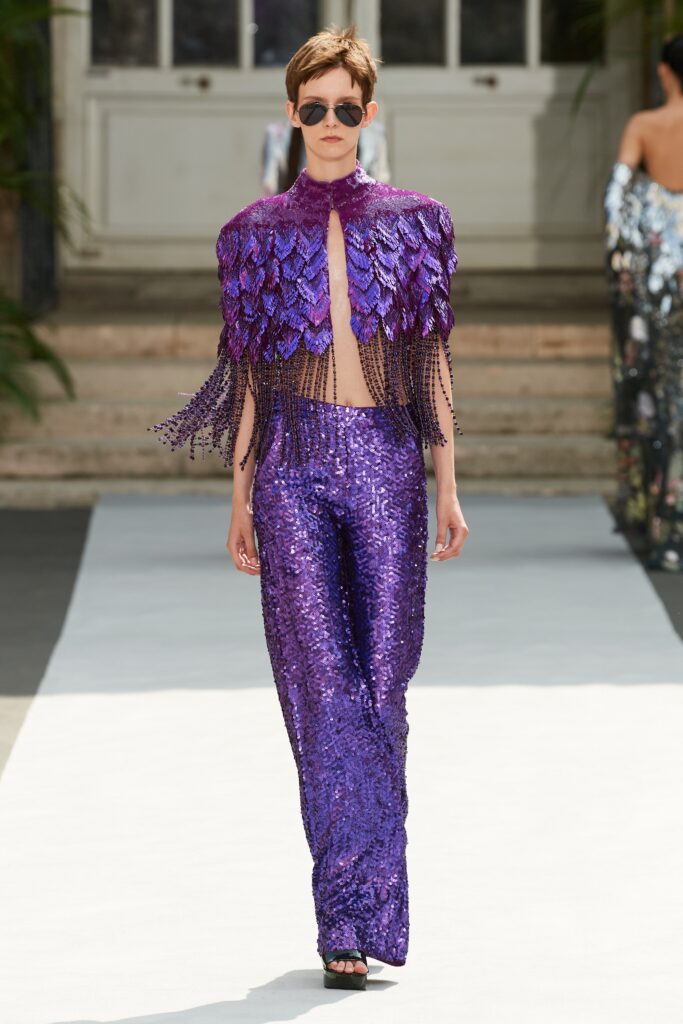 A fitted purple sequin sleeveless top with a layered design and matching fitted pants.