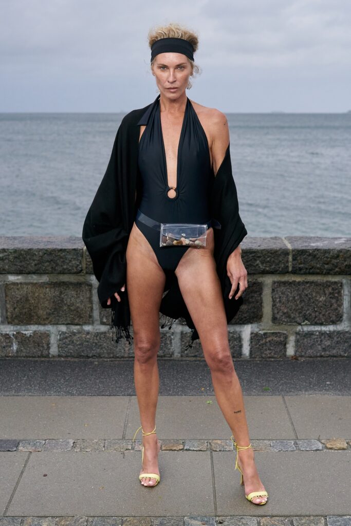 A fitted black halter swimsuit paired with a flowing silk cape for a chic beach look.