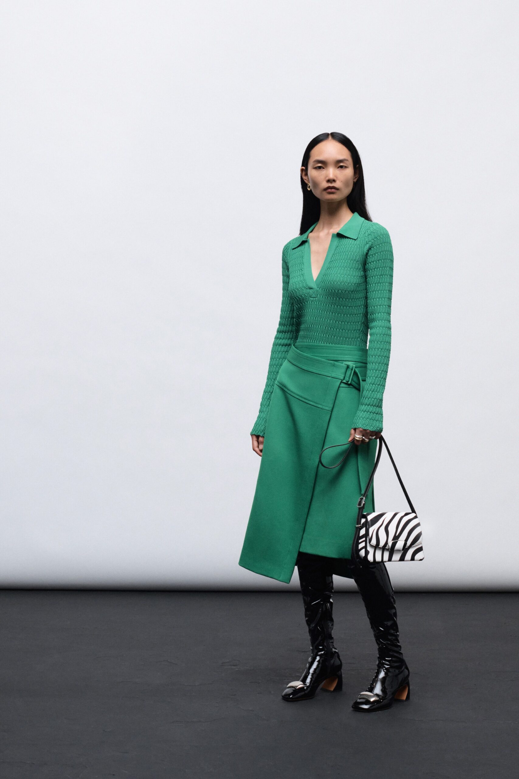A fitted green long-sleeve dress with a V-neckline and asymmetric design.