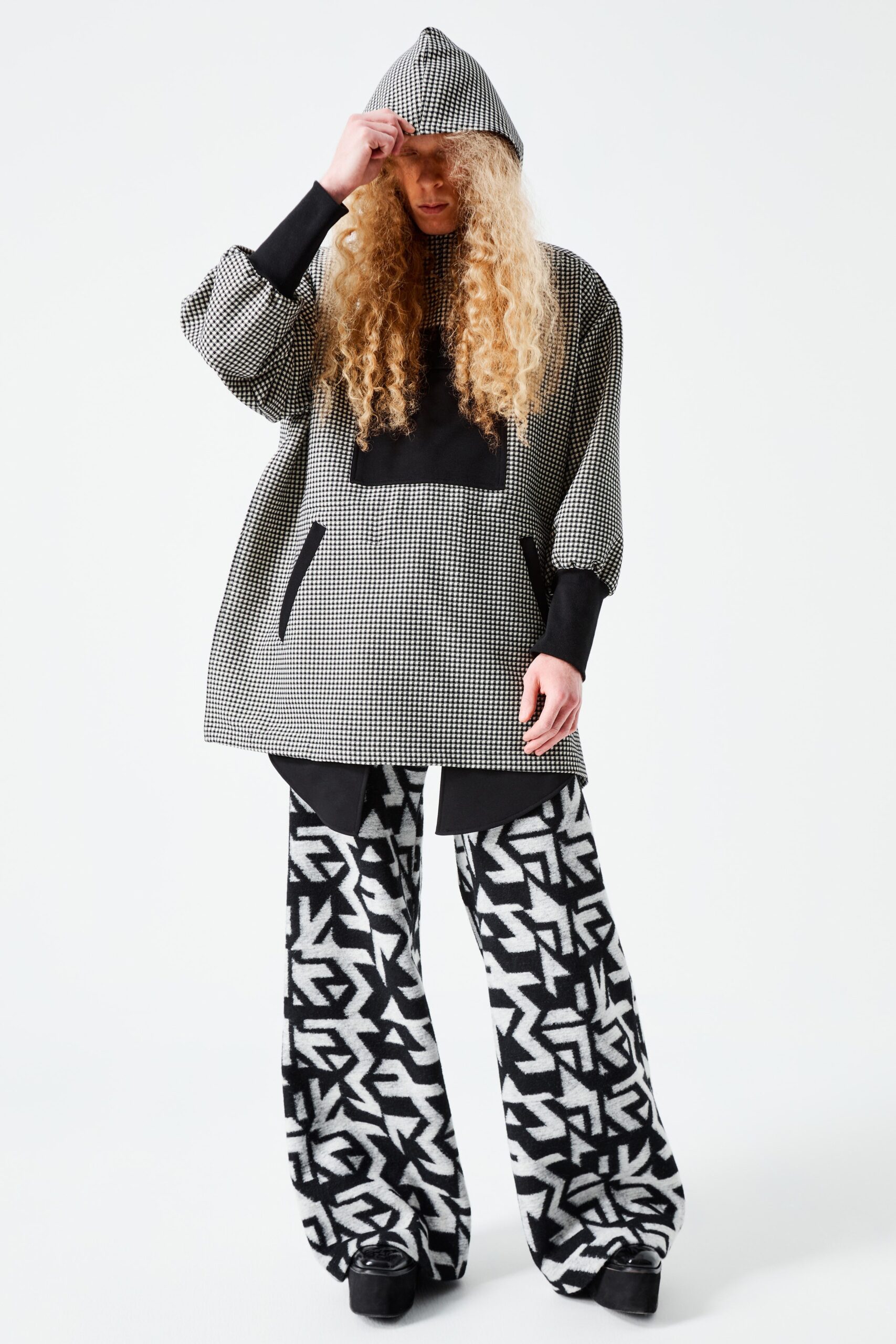 This relaxed hoodie features a striking black and white print, complemented by wide-leg pants that echo the graphic motif. The combination creates a bold silhouette, while the hood adds an element of casual comfort, making a statement in both pattern and proportion.