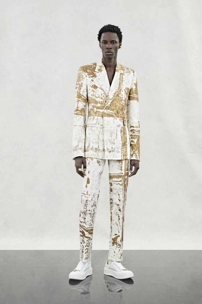 A tailored white suit with gold print and long sleeves, featuring a collared design.