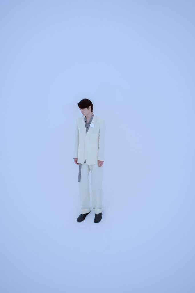 A tailored white suit with a collared shirt and long sleeves, featuring a buttoned design.