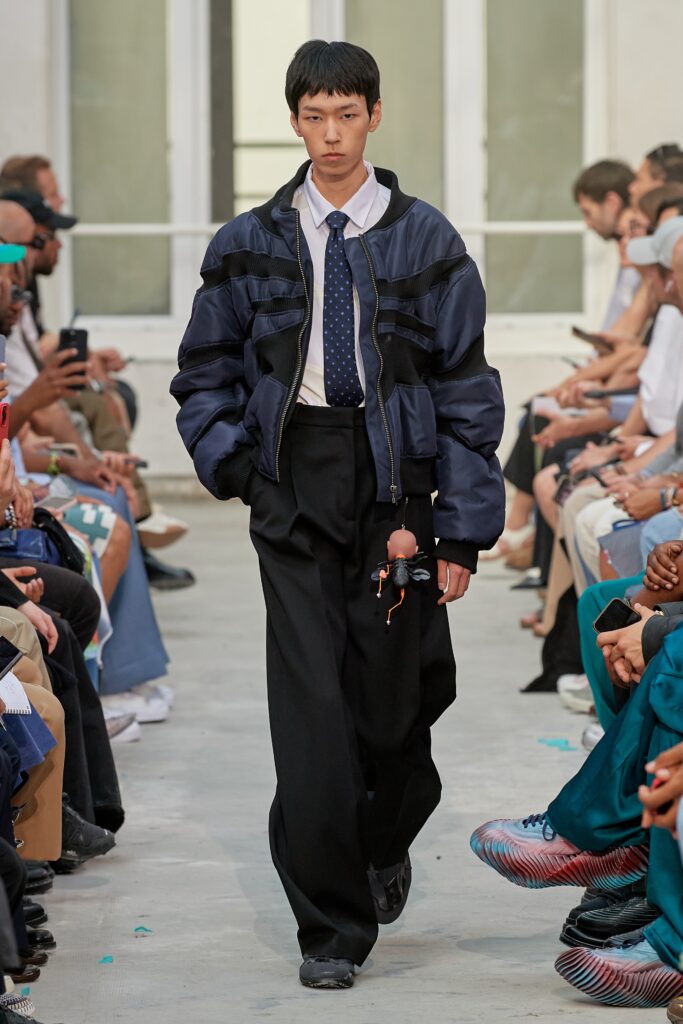 A relaxed blue cotton jacket with long sleeves paired with wide-leg black pants.