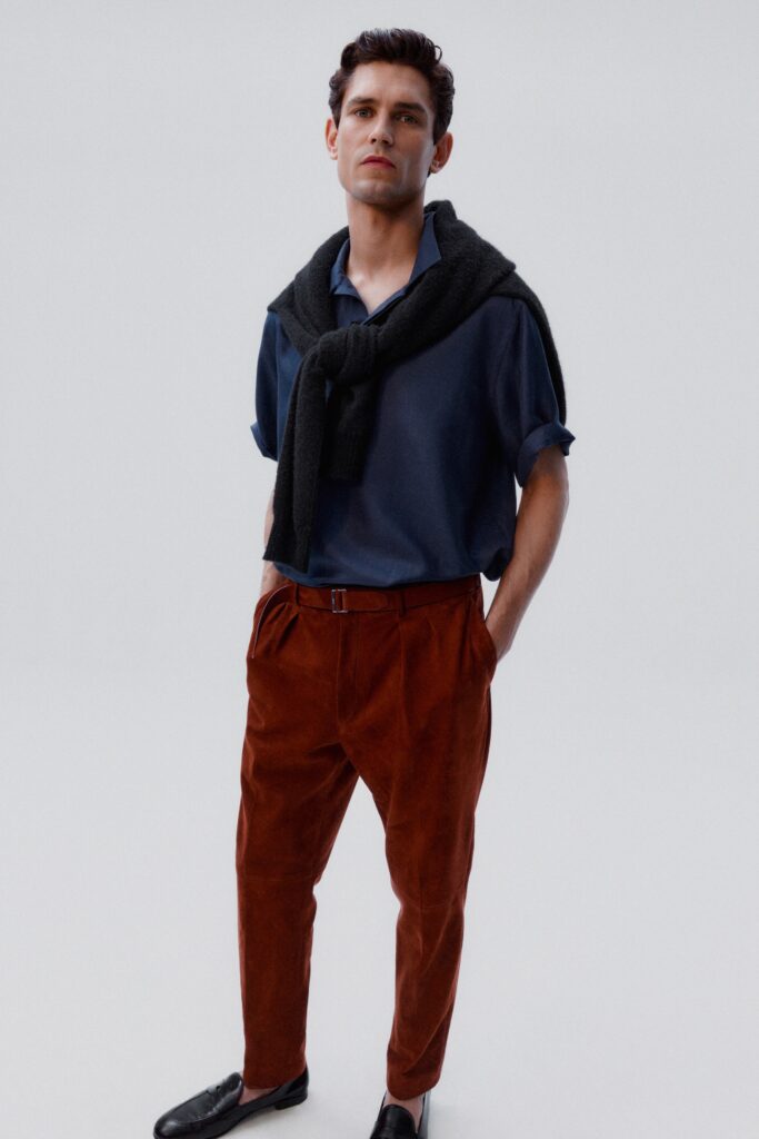 A relaxed blue short-sleeve shirt paired with high-waisted pleated brown pants.