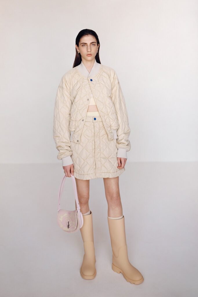 A fitted beige quilted jacket with a collared neckline paired with a matching skirt.