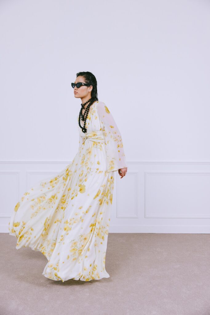 A relaxed white dress with yellow floral patterns, featuring long sleeves and a V-neckline.