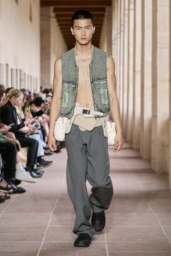 A relaxed gray cotton sleeveless vest layered over pants with a unique zippered design.
