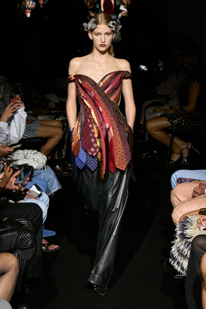 A fitted multicolor sleeveless top with an asymmetric design paired with sleek black pants.