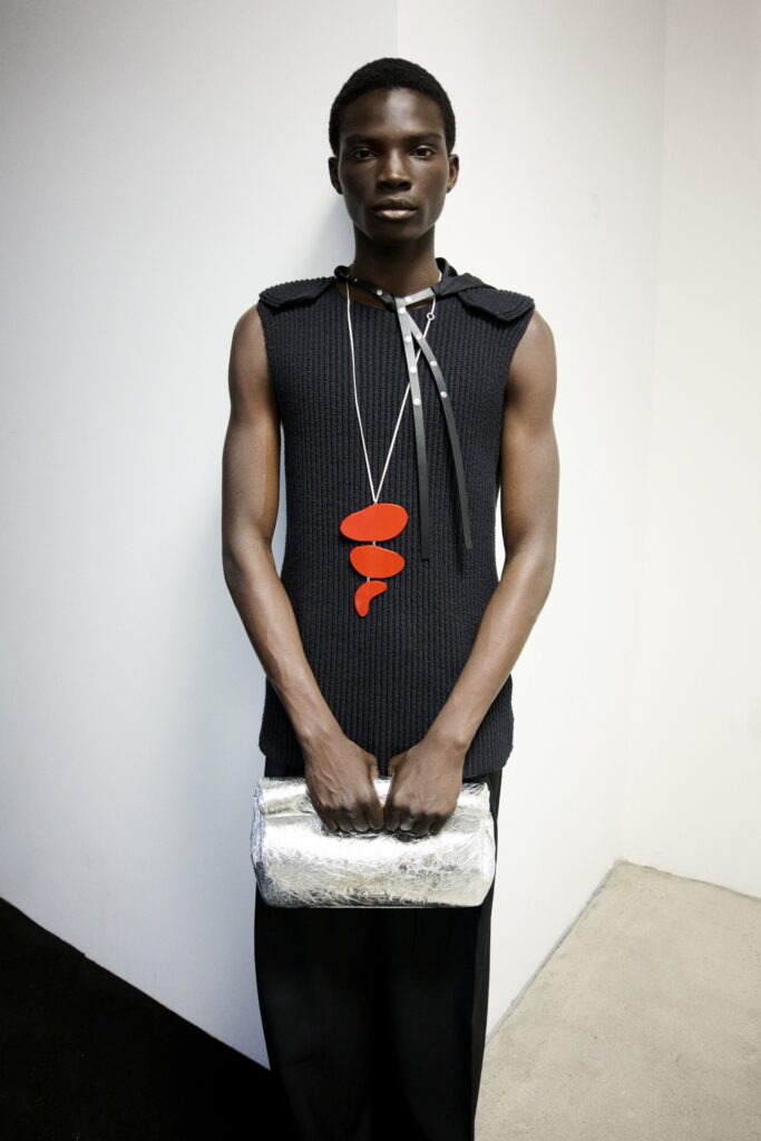 A fitted black sleeveless top with a V-neck and layered design paired with black pants.