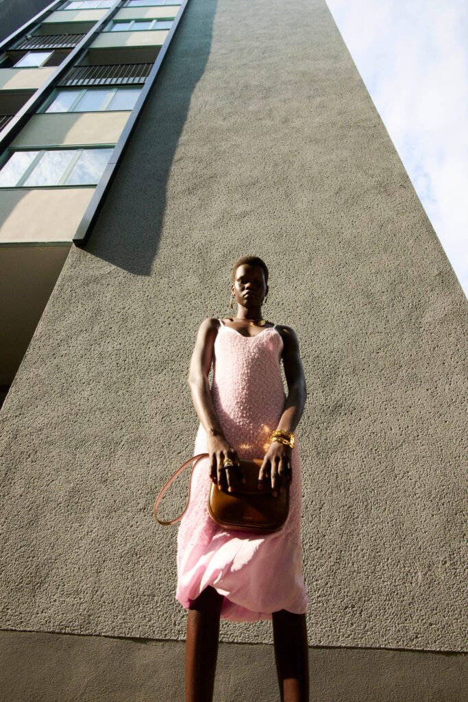A fitted pink silk dress with a sleeveless design and tiered details.