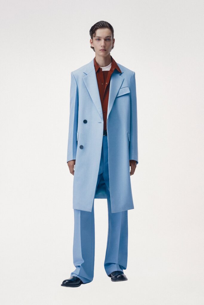 A fitted blue cotton coat with a collared neckline paired with straight-leg pants.