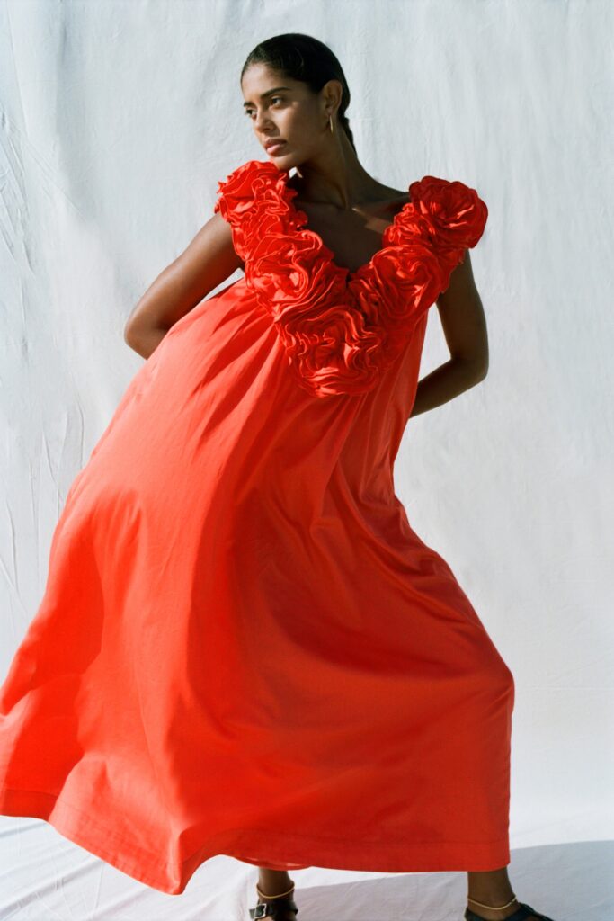 A relaxed red cotton sleeveless dress featuring a V-neckline and ruffled detailing.